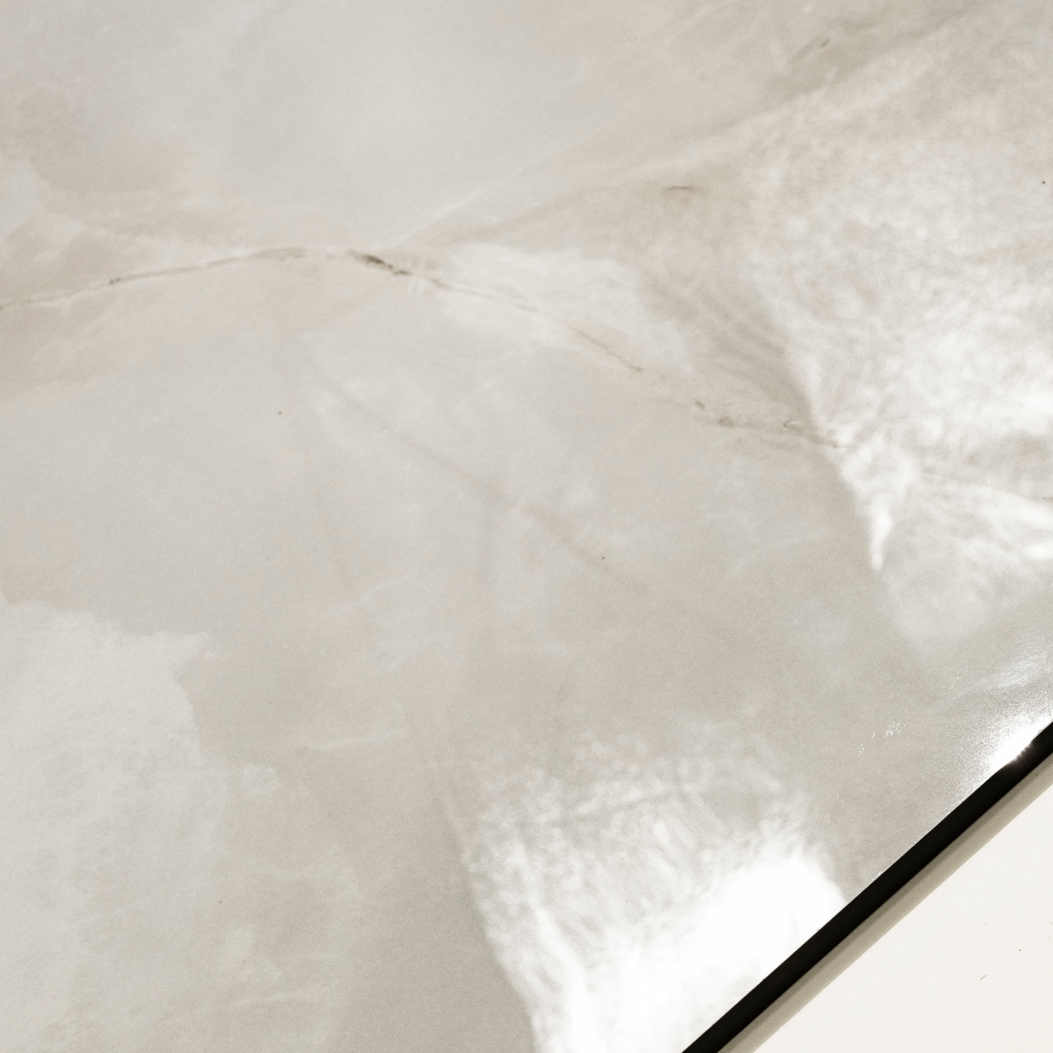 Close-up detail showing the translucent onyx pattern and mirror-gloss surface of Marbella Gold porcelain tile