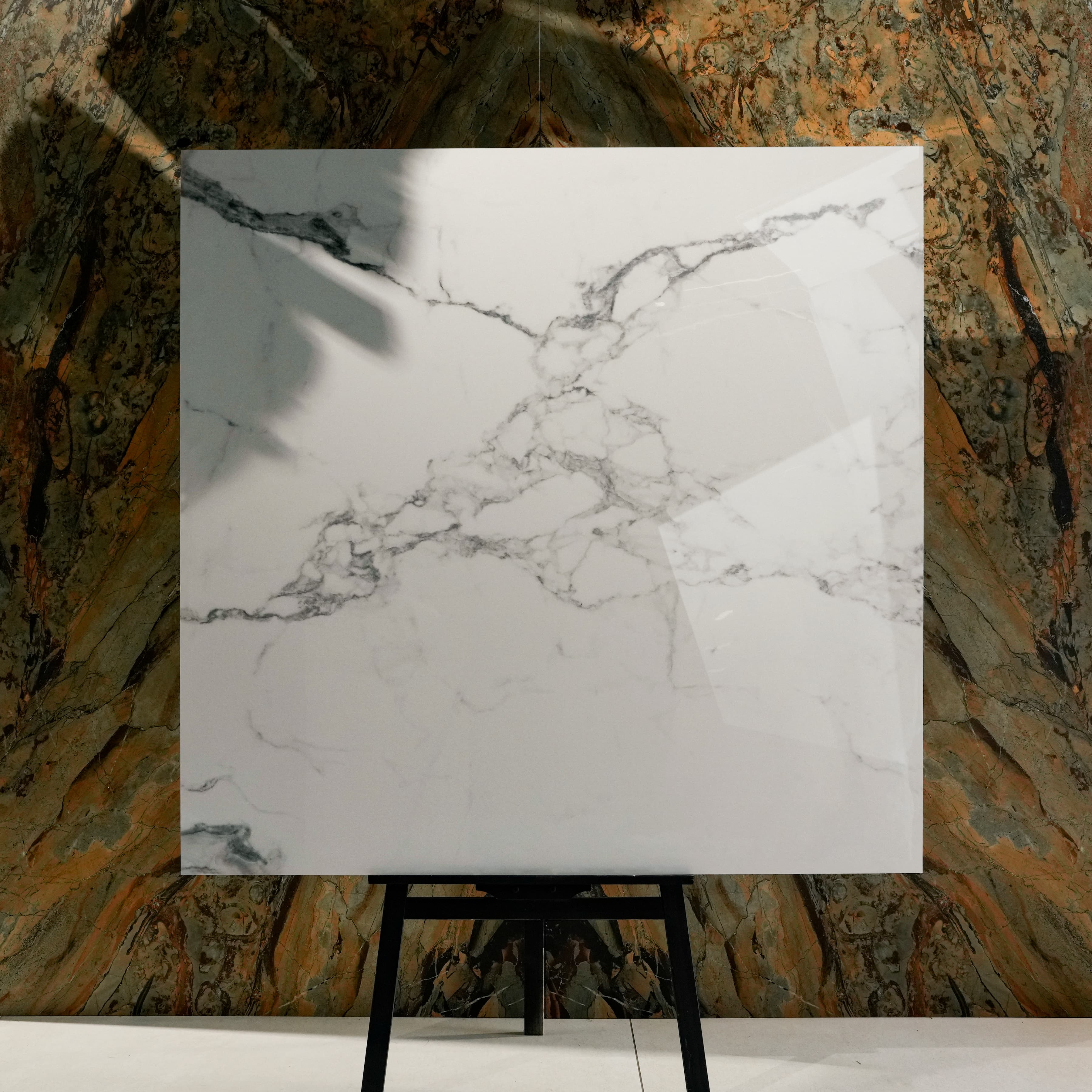 Staturio Krypton Glossy 120x120 porcelain tile displayed on easel against natural marble backdrop in UAE showroom