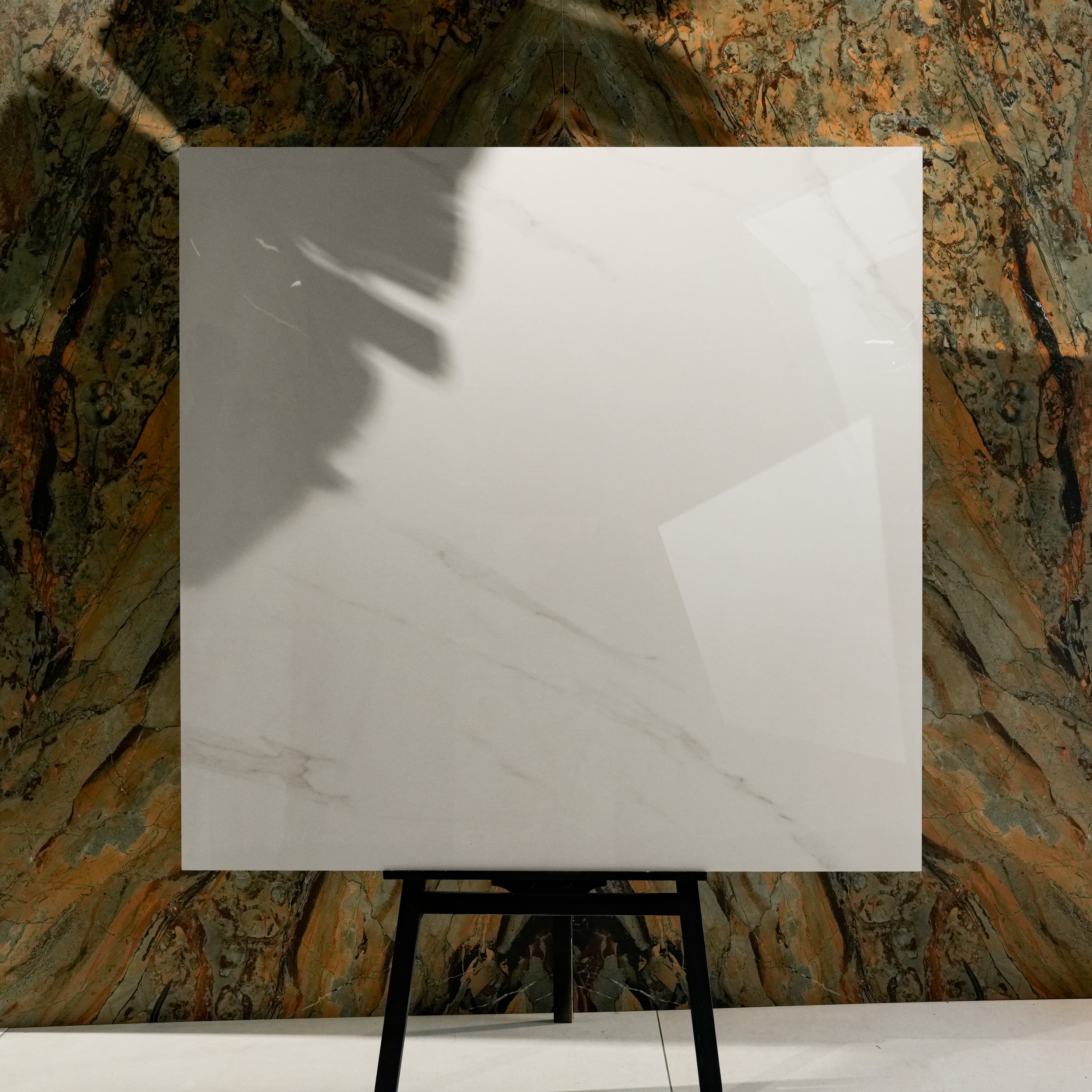 Smoke White Glossy 120x120 porcelain tile displayed on easel against natural marble backdrop in UAE showroom