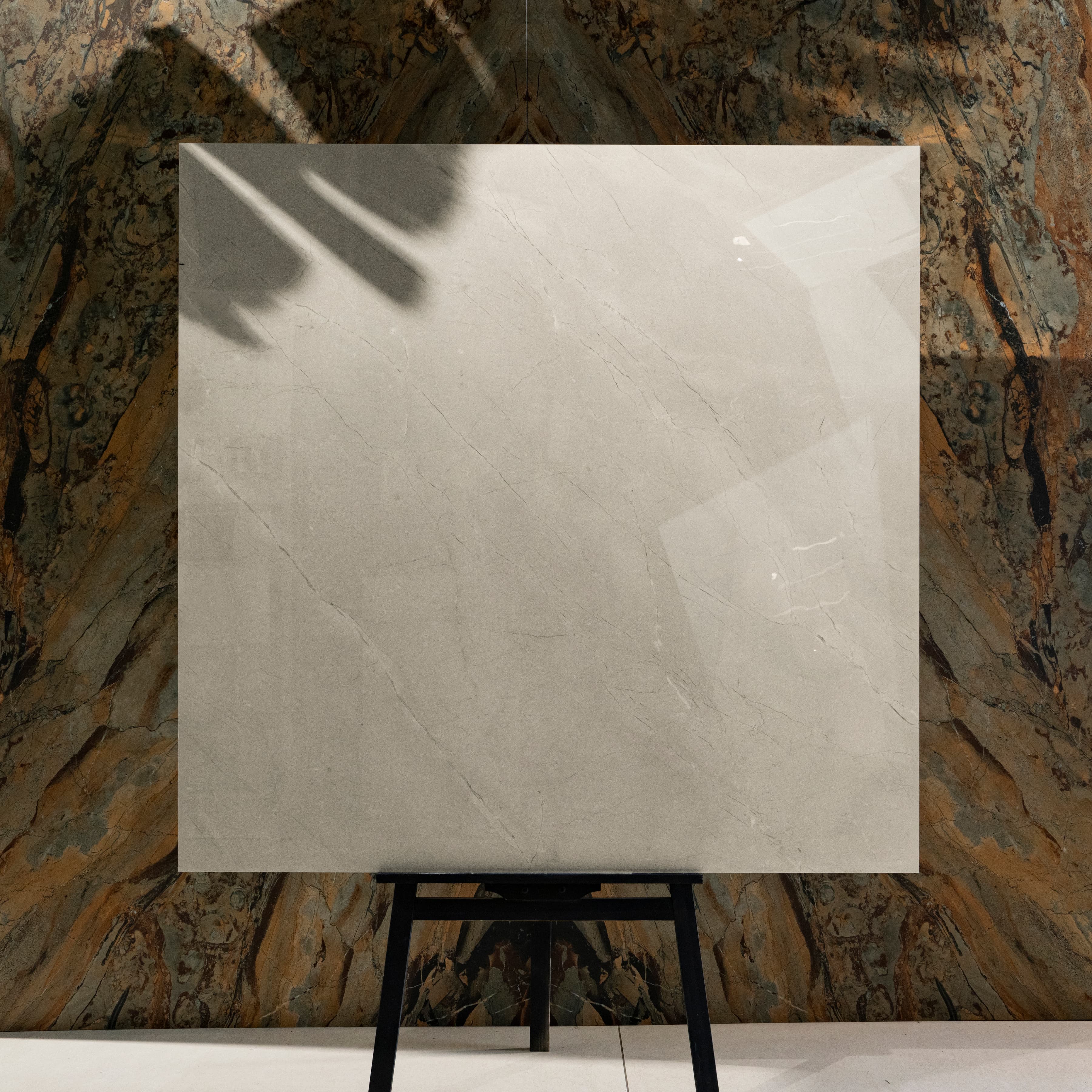 Burberry Bianco 120x120cm British heritage cream marble look high-gloss polished porcelain tile on easel against onyx marble backdrop in UAE luxury tile showroom