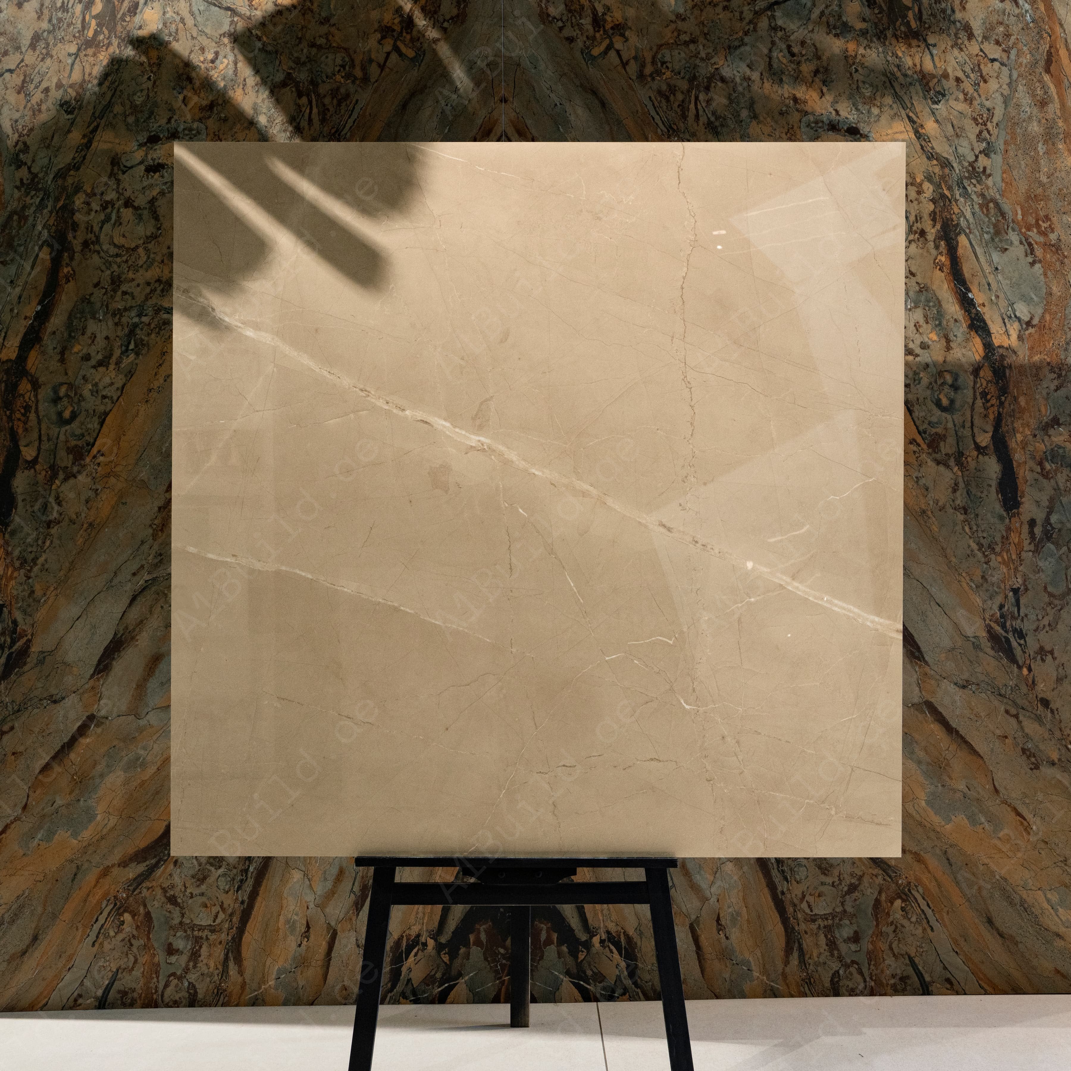 Armani Beige 120x120cm warm Italian Crema Marfil look glossy polished porcelain tile on easel against onyx marble backdrop in UAE luxury tile showroom