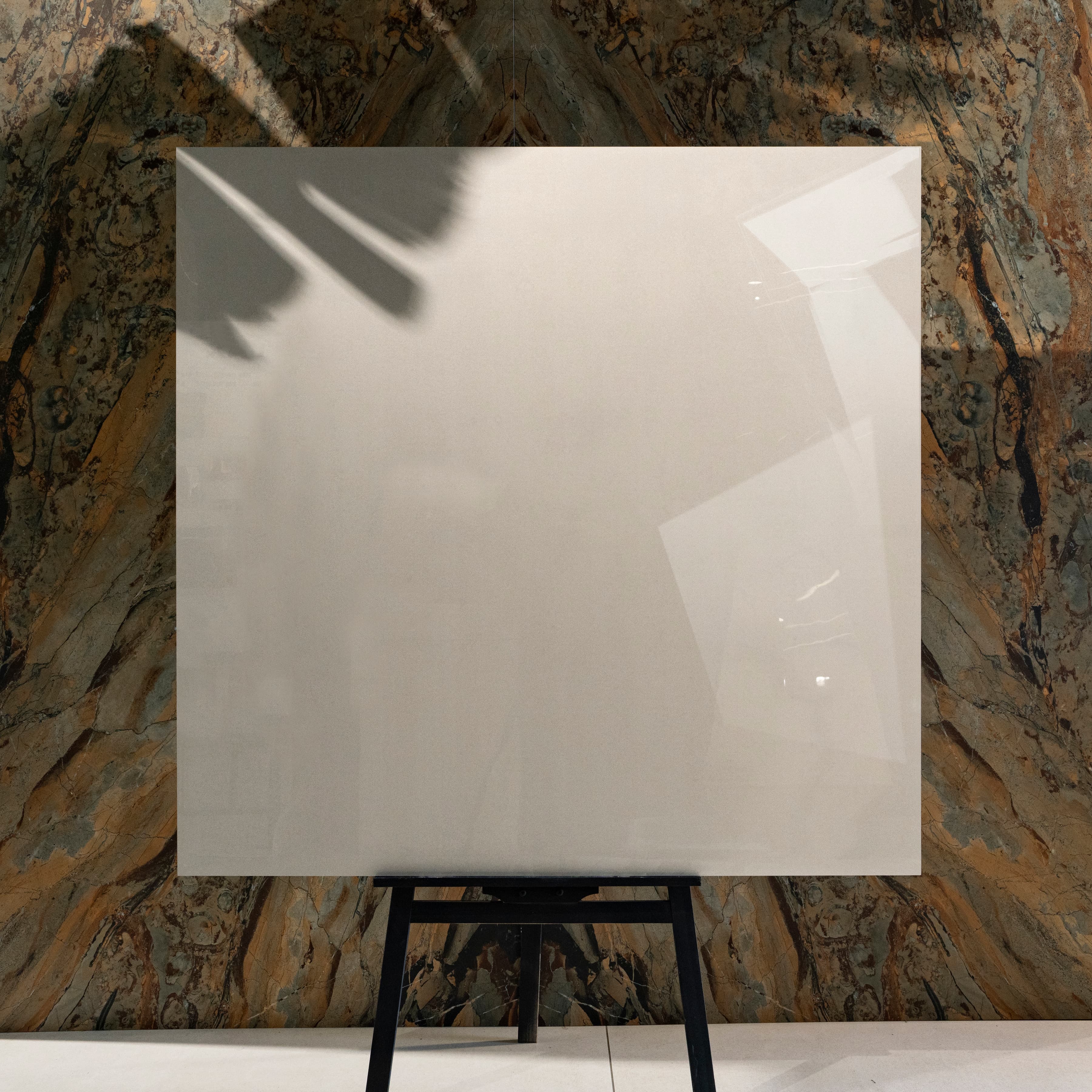 Portland Bianco glossy porcelain tile 120x120cm on easel against luxury marble backdrop for UAE interiors