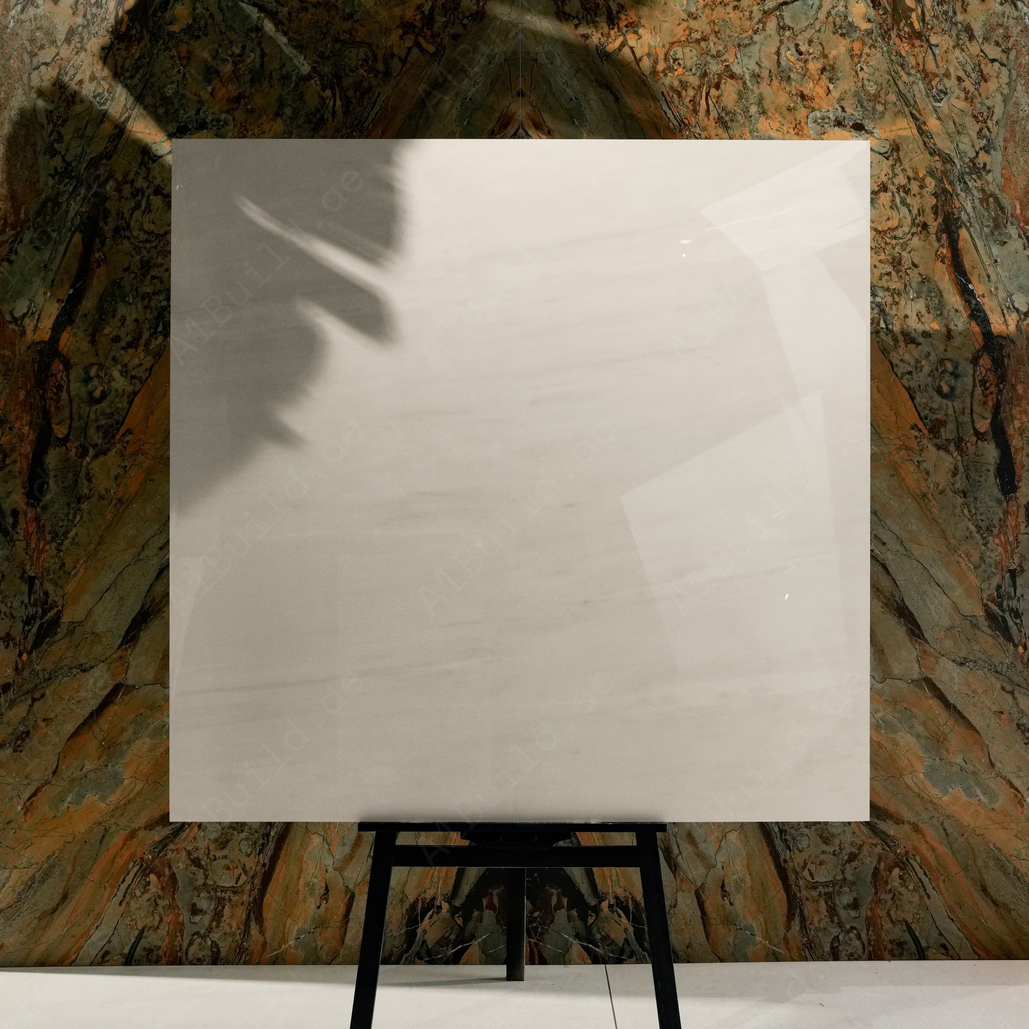 Melton Bianco Glossy 120x120 porcelain tile displayed on easel against natural marble backdrop in UAE showroom