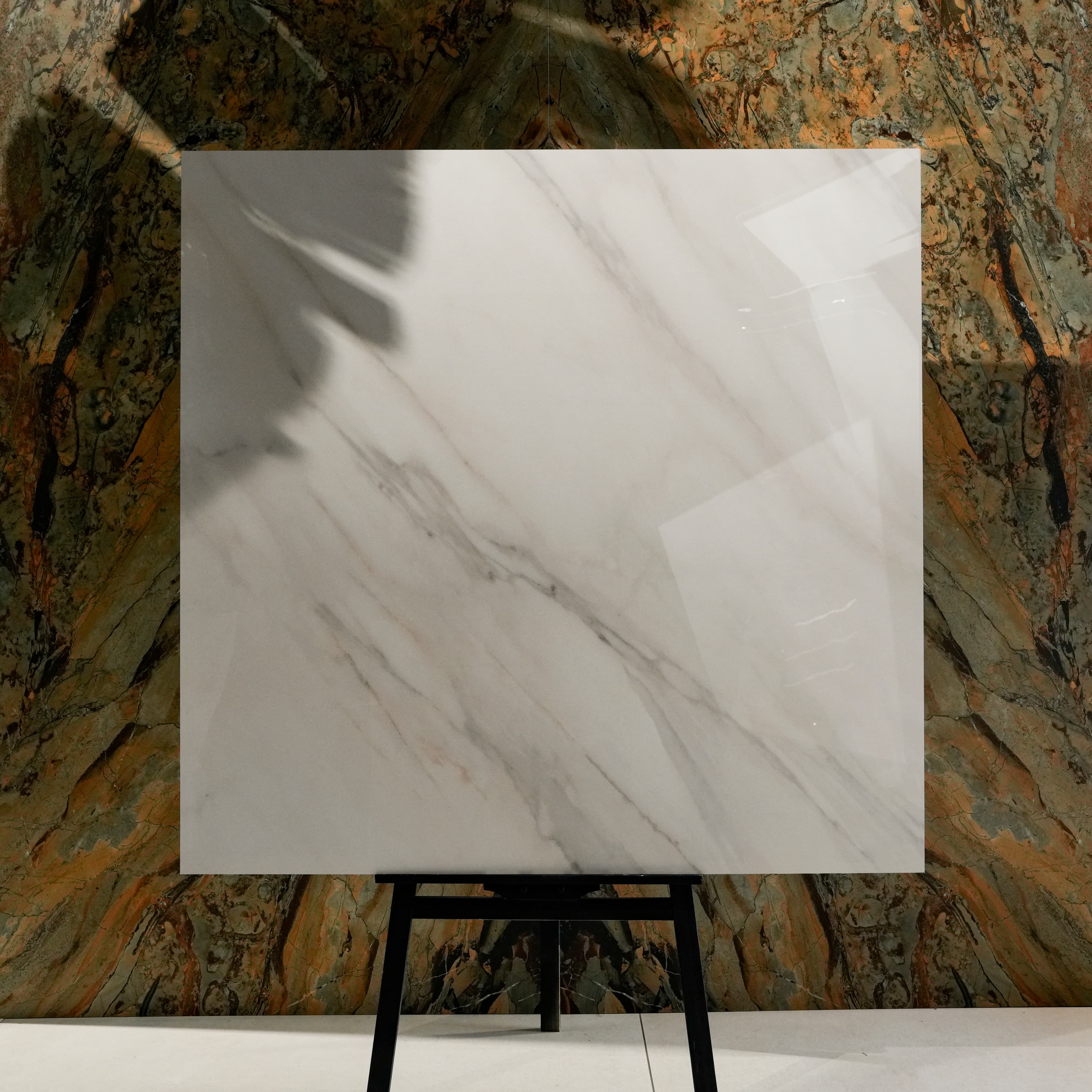 Calcutta Aurora Glossy 120x120 porcelain tile displayed on easel against natural marble backdrop in UAE showroom