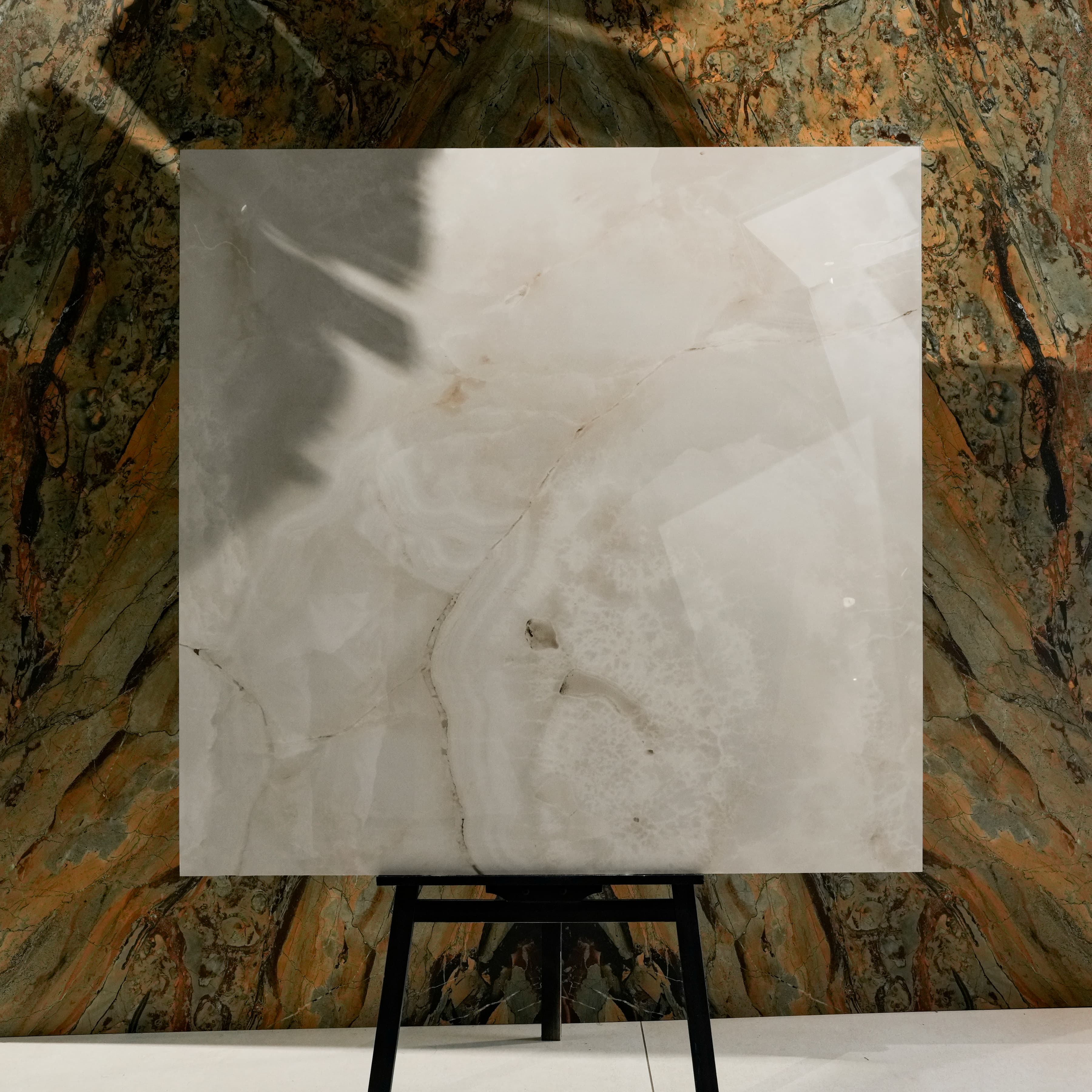 Marbella Gold Glossy 120x120 porcelain tile displayed on easel against natural marble backdrop in UAE showroom