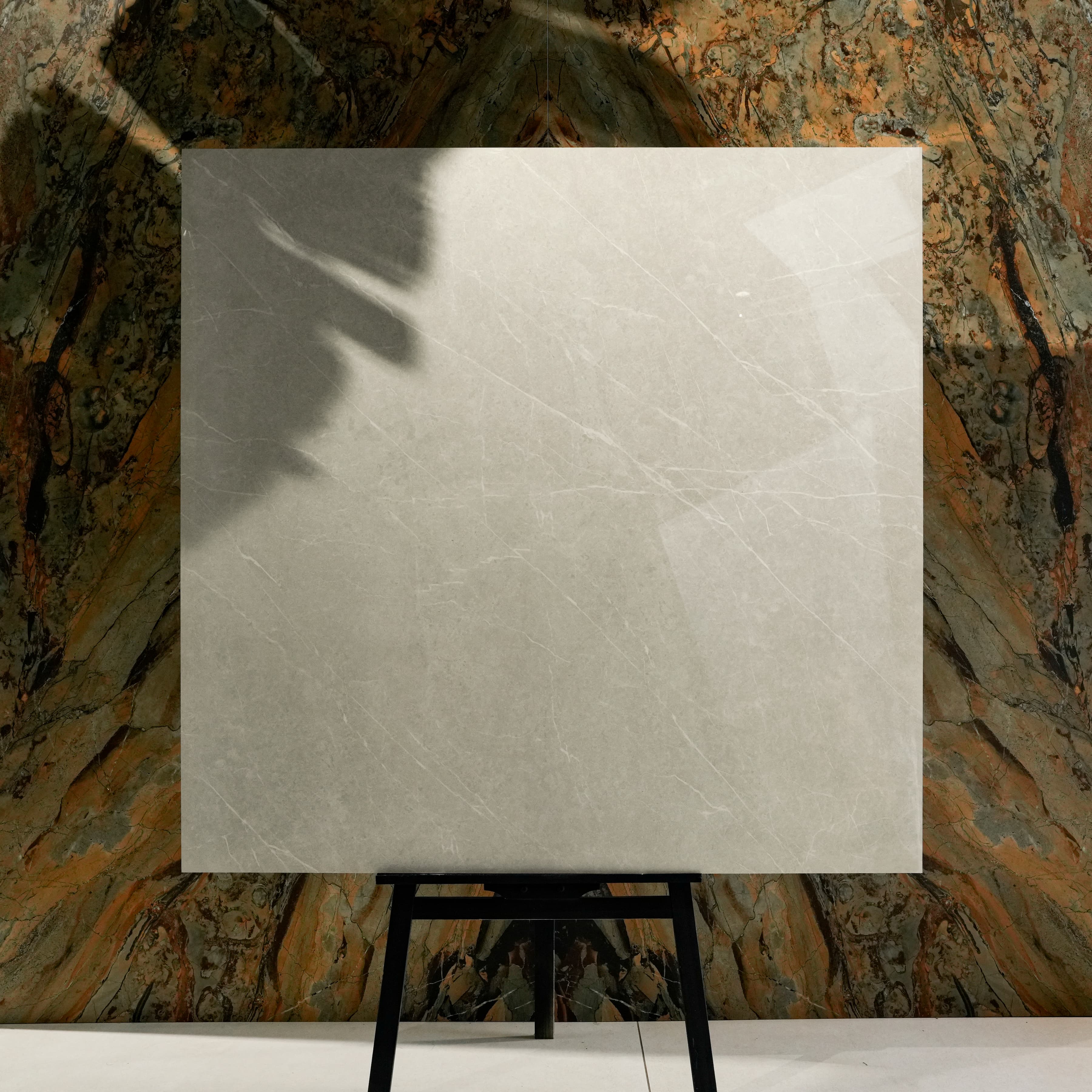 Pietra Bianco Glossy 120x120 porcelain tile displayed on easel against natural marble backdrop in UAE showroom