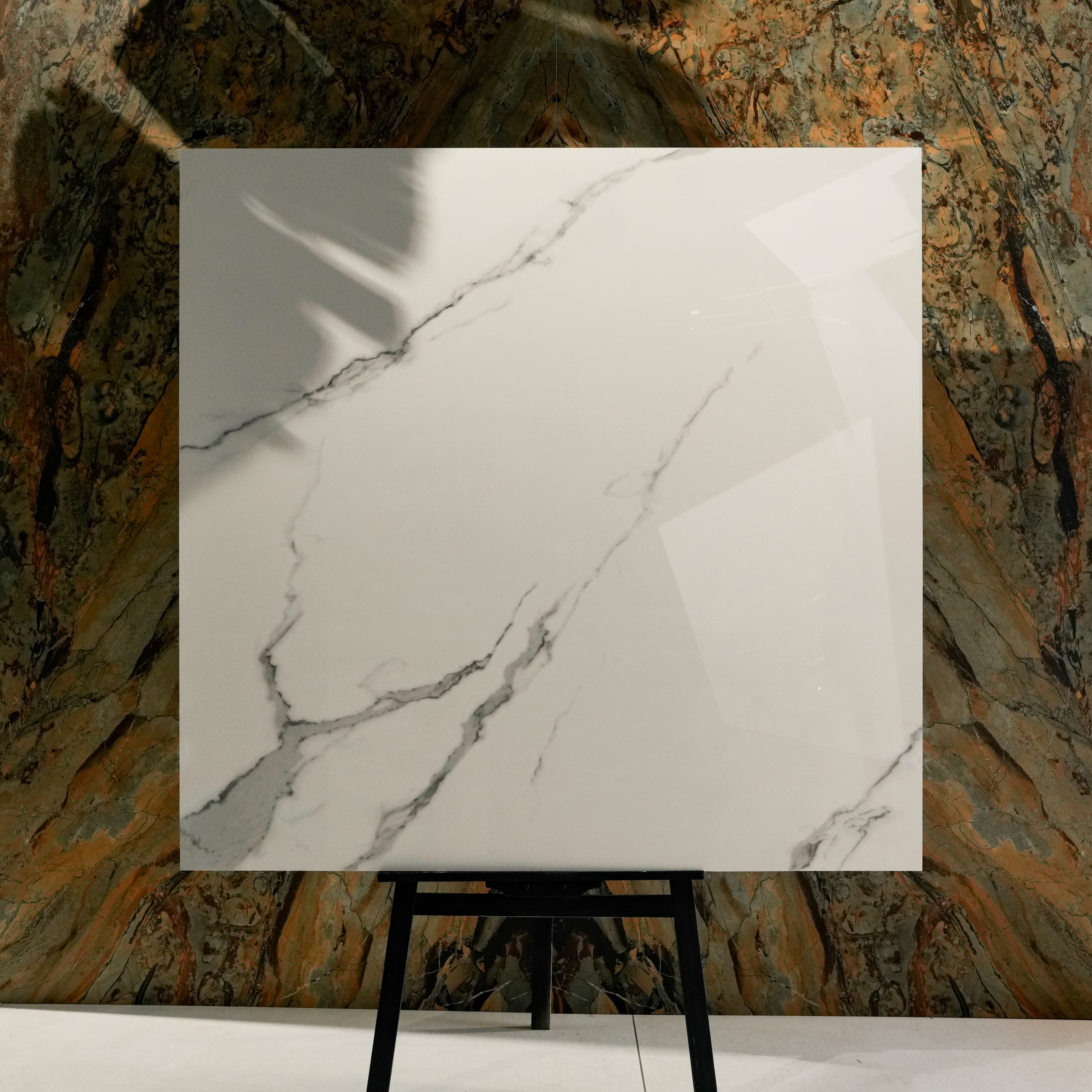 Statuario Hexa Glossy 120x120 porcelain tile displayed on easel against natural marble backdrop in UAE showroom
