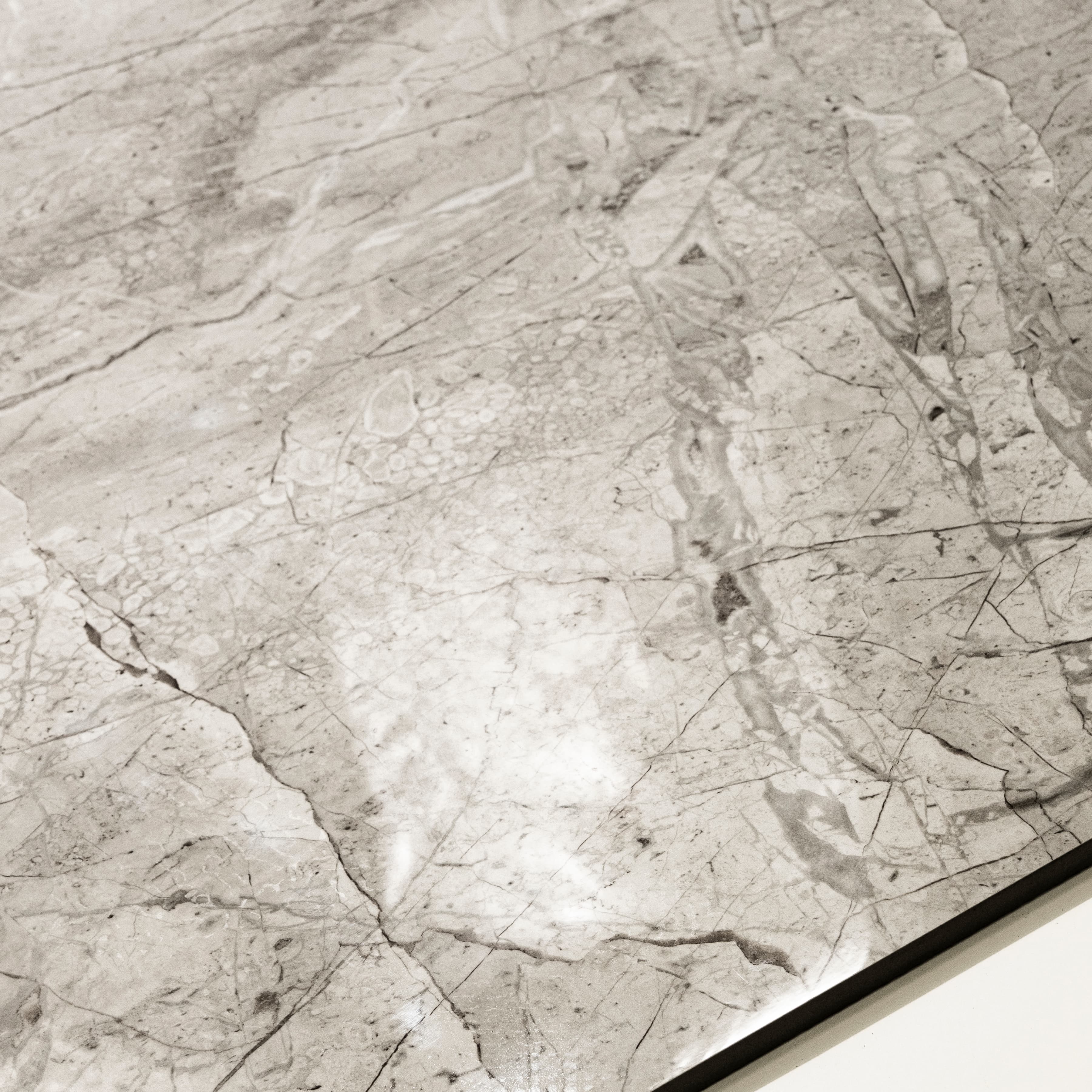 Close-up detail showing the dense fissure network and mirror-gloss surface of Breccia Bianco porcelain tile