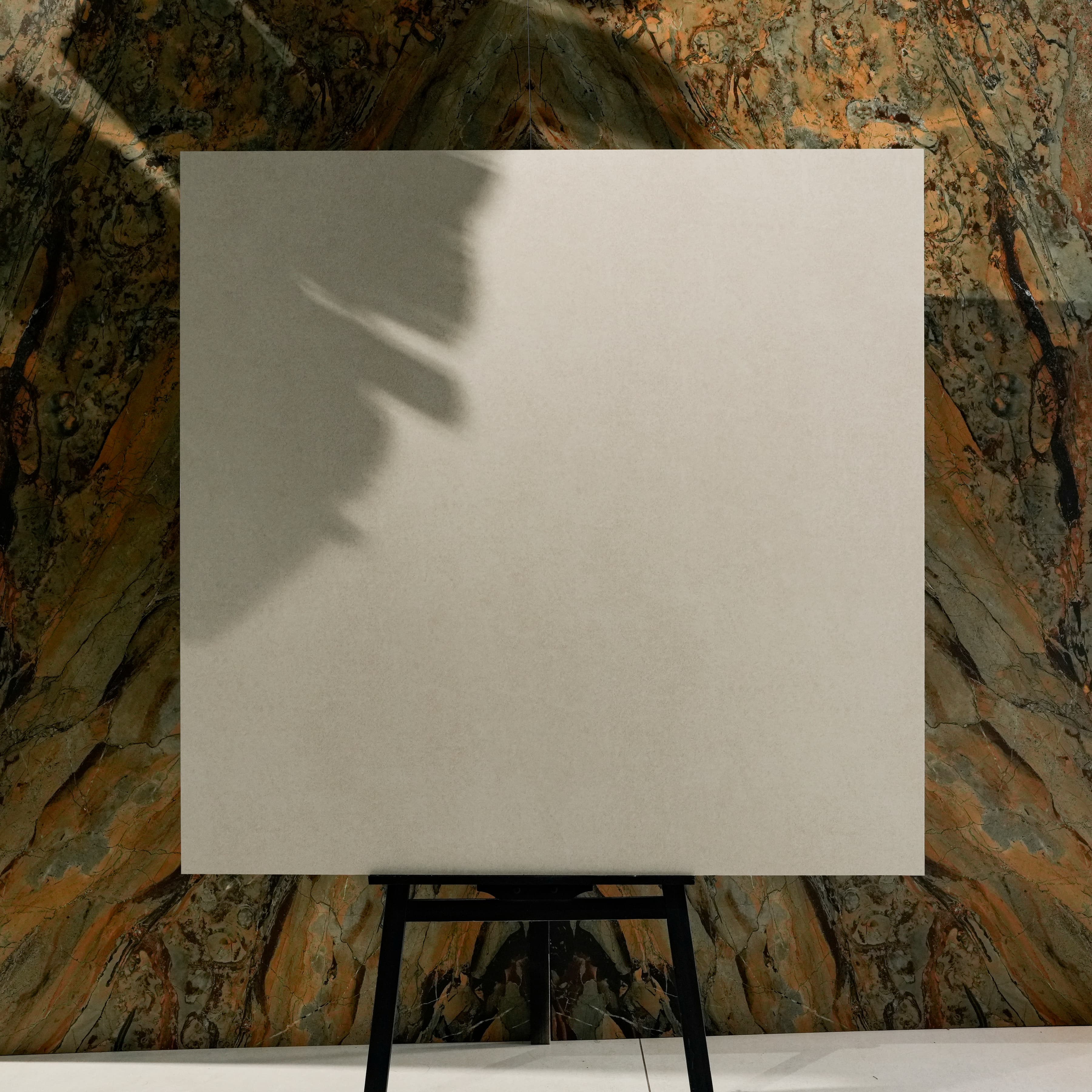 Norway Cemento Bianco 120x120cm matte porcelain tile displayed on easel against onyx marble backdrop in luxury UAE showroom setting