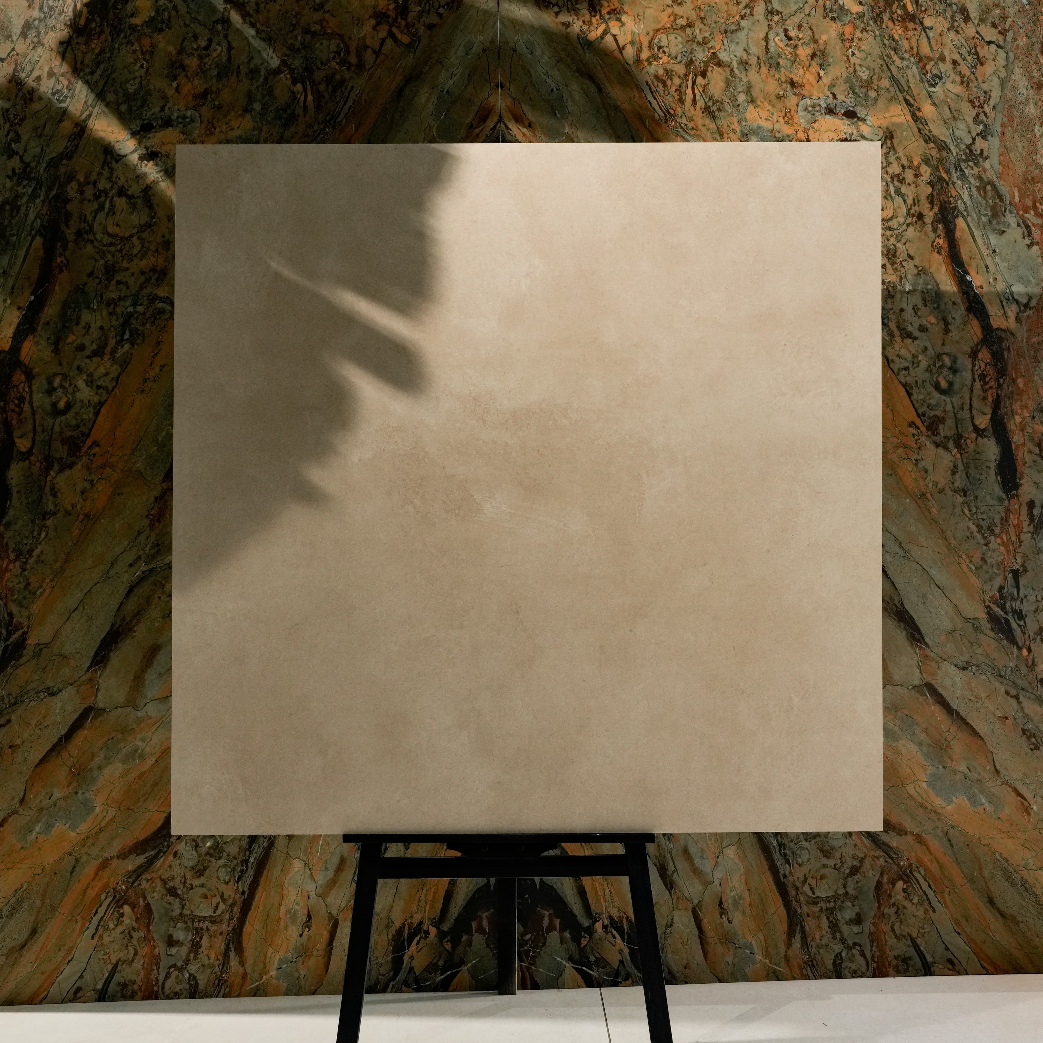 Azure Crema Lite 120x120cm warm beige matte porcelain tile on easel against onyx marble backdrop in UAE luxury tile showroom