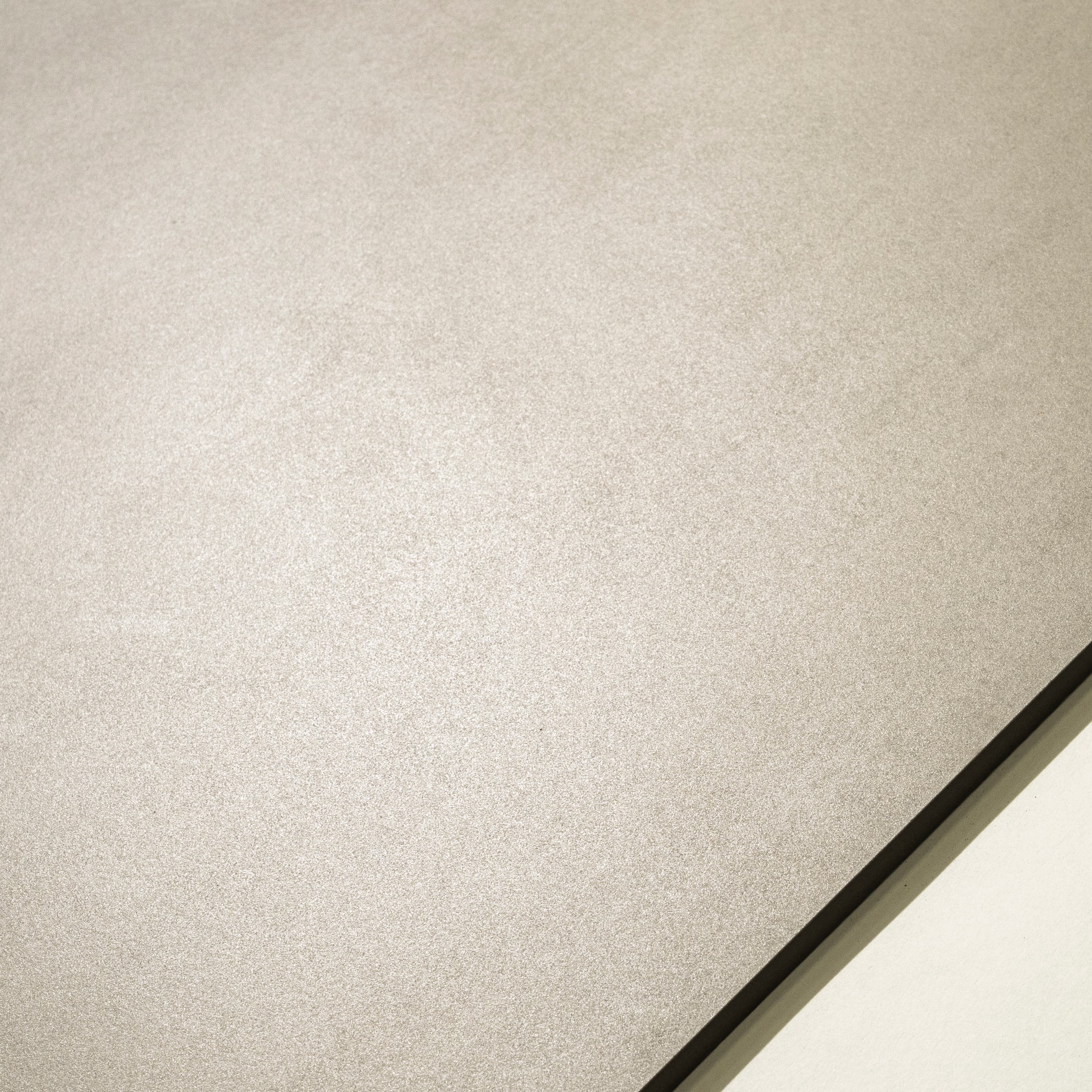 Close-up of Portland Bianco matte porcelain surface showing fine sanded plaster texture in warm white-grey