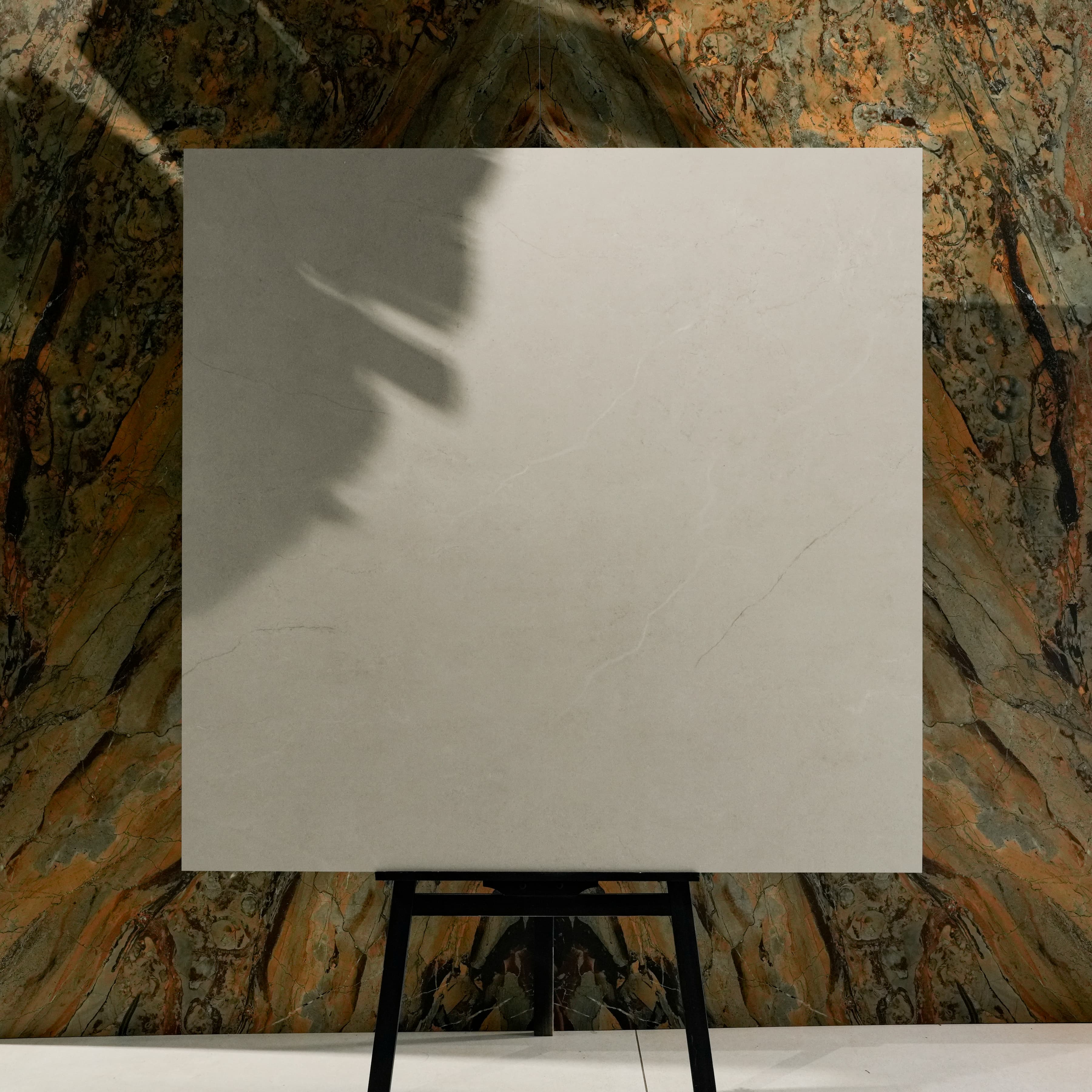 Oslo Pearl New 120x120cm pearl white marble effect matte porcelain tile on easel against onyx marble backdrop in UAE luxury tile showroom