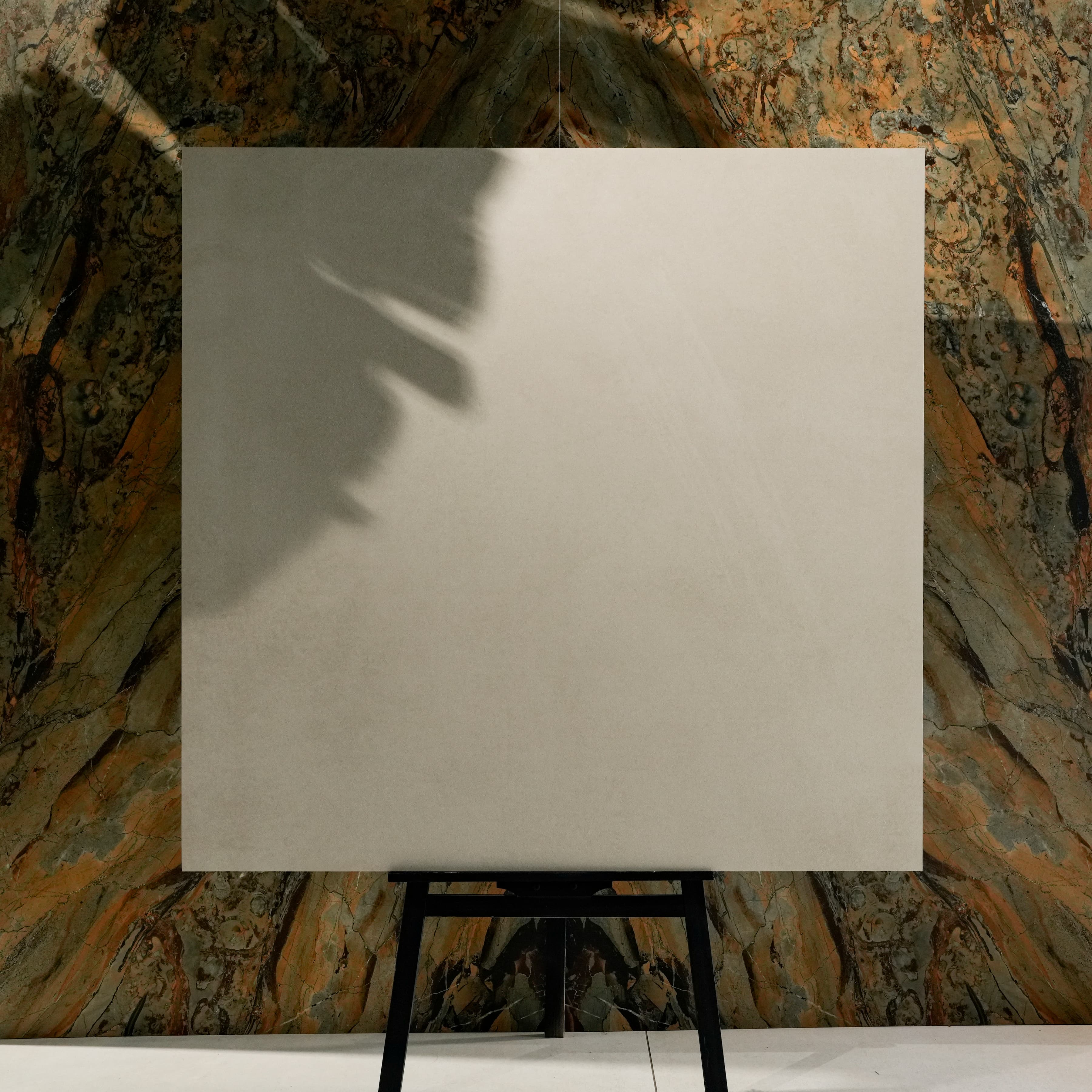 Icona Bianco 120x120cm iconic Italian warm white matte porcelain tile on easel against onyx marble backdrop in luxury UAE tile showroom