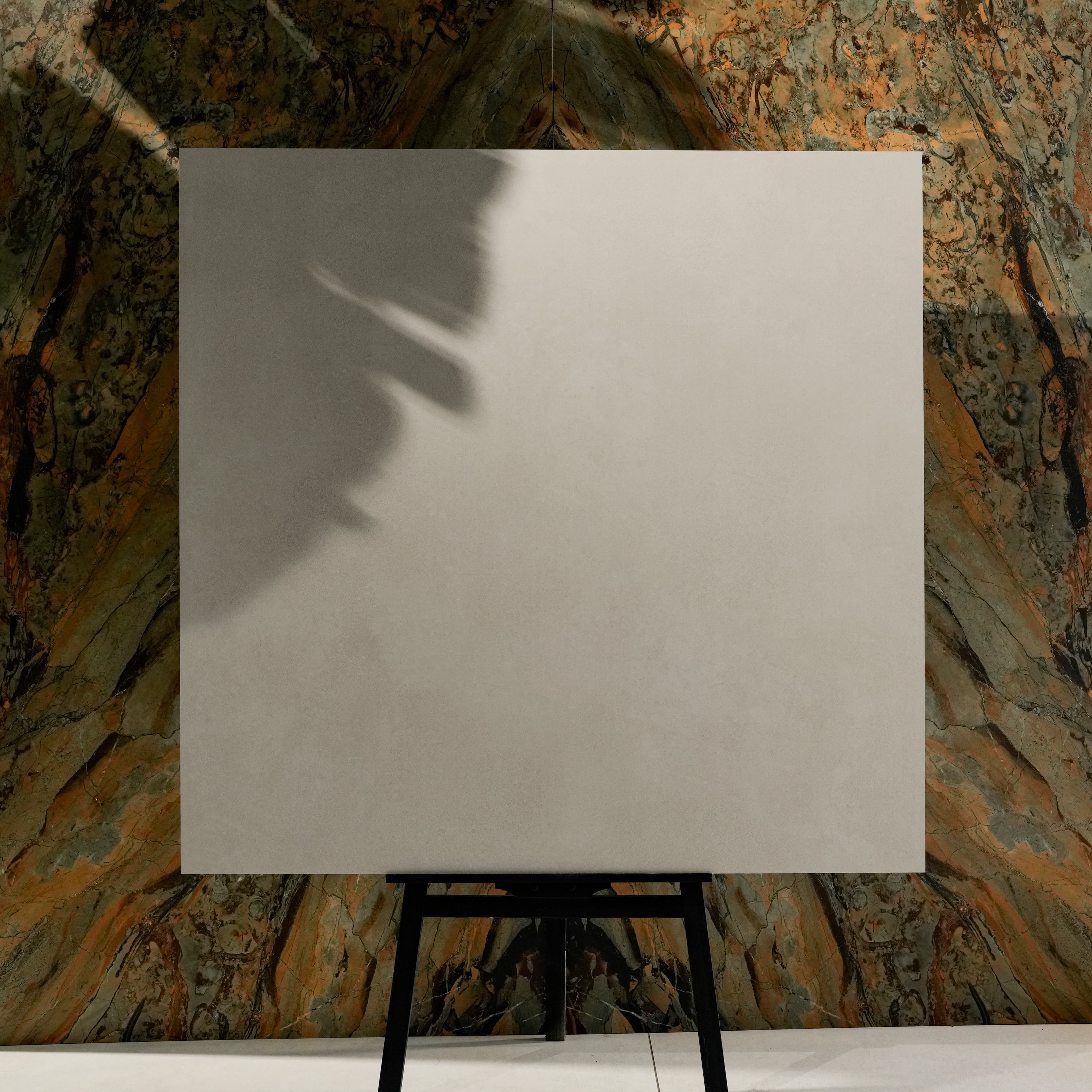 Meeray Grey 120x120cm soft warm grey matte porcelain tile on easel against onyx marble backdrop in luxury UAE tile showroom