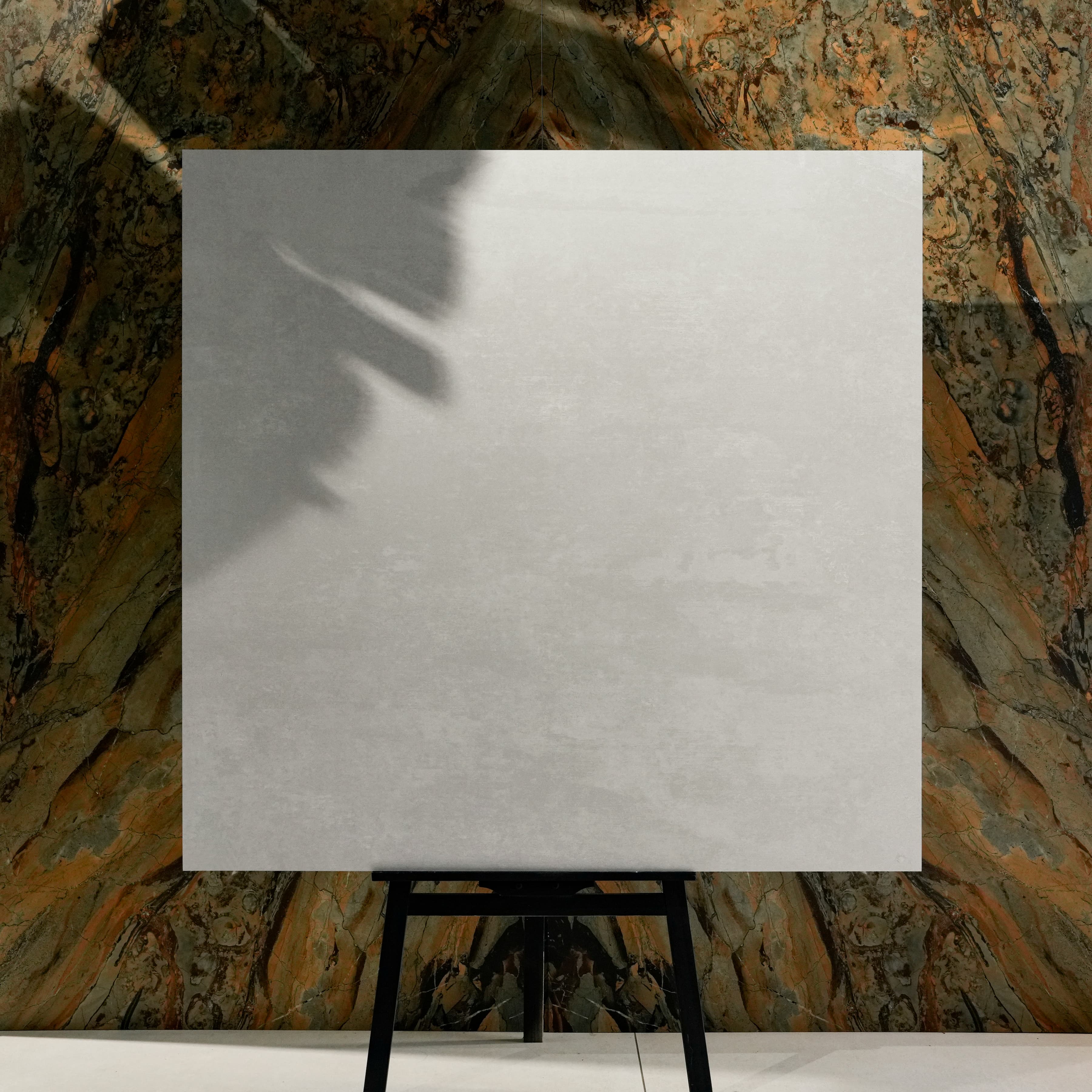 Granite White 120x120cm modern brushed white matte porcelain tile on easel against onyx marble backdrop in UAE luxury tile showroom