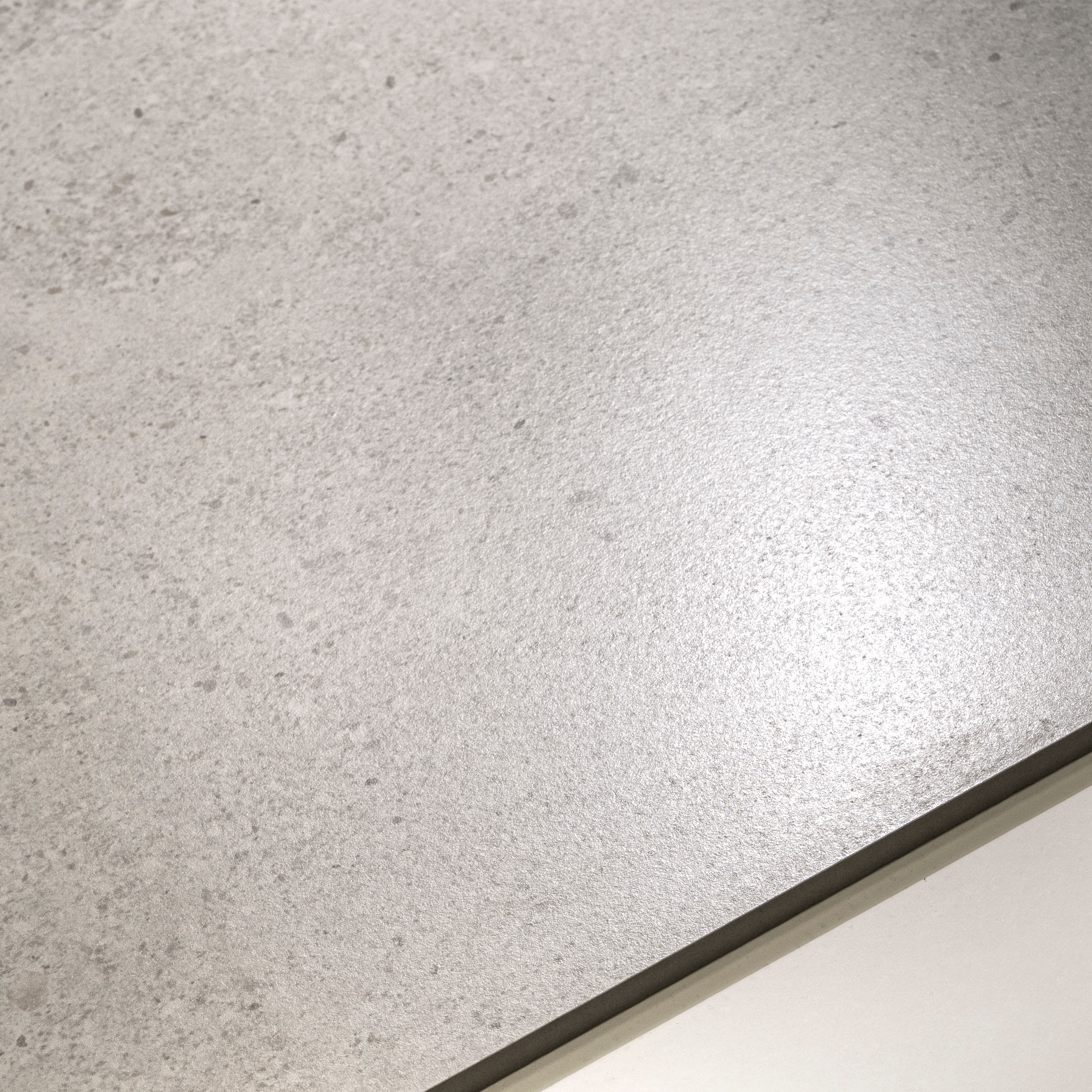 Close-up of Ferro White matte porcelain surface revealing scattered dark mineral speckles across warm cream base