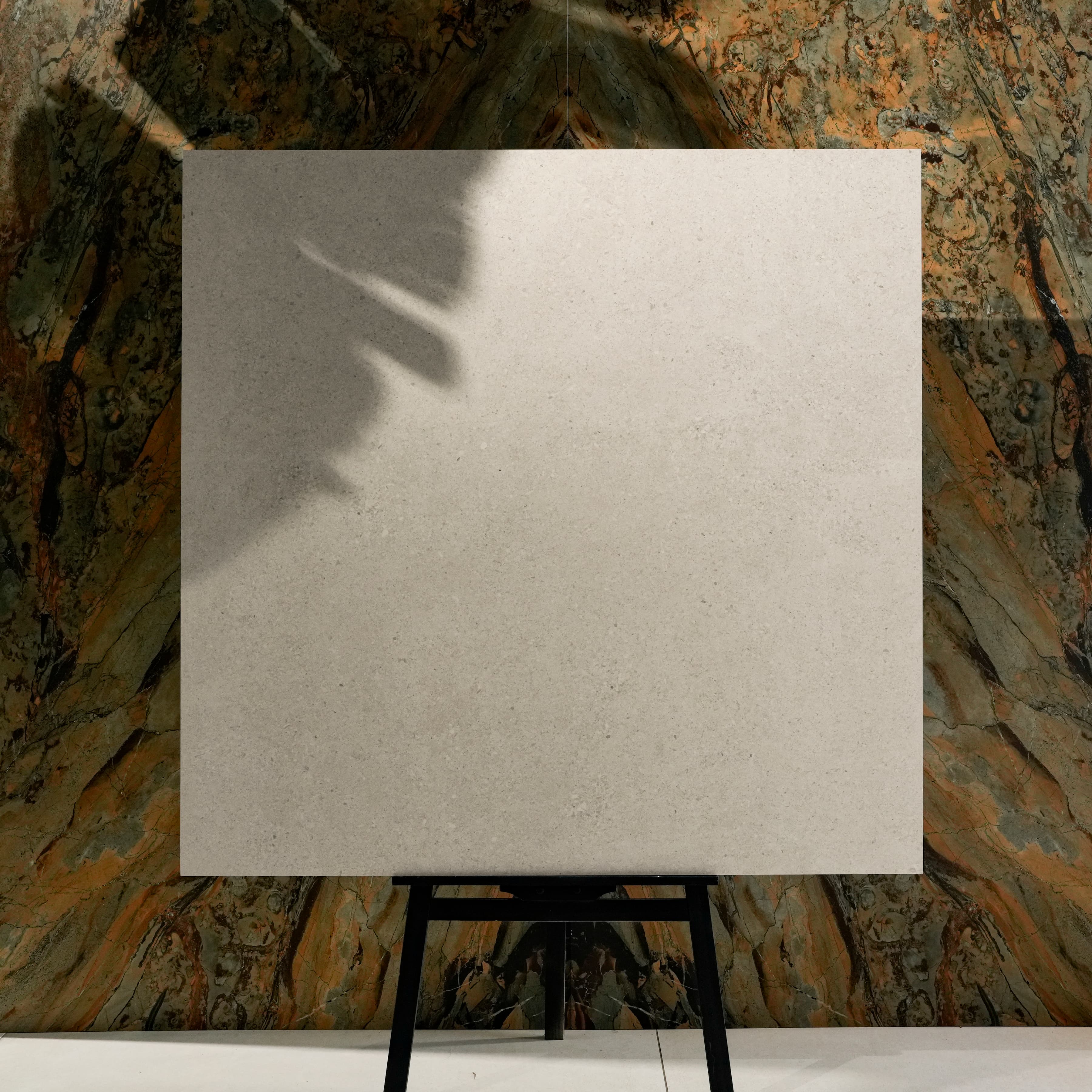 Ferro White 120x120cm warm cream speckled matte porcelain tile on easel against onyx marble backdrop in UAE luxury tile showroom