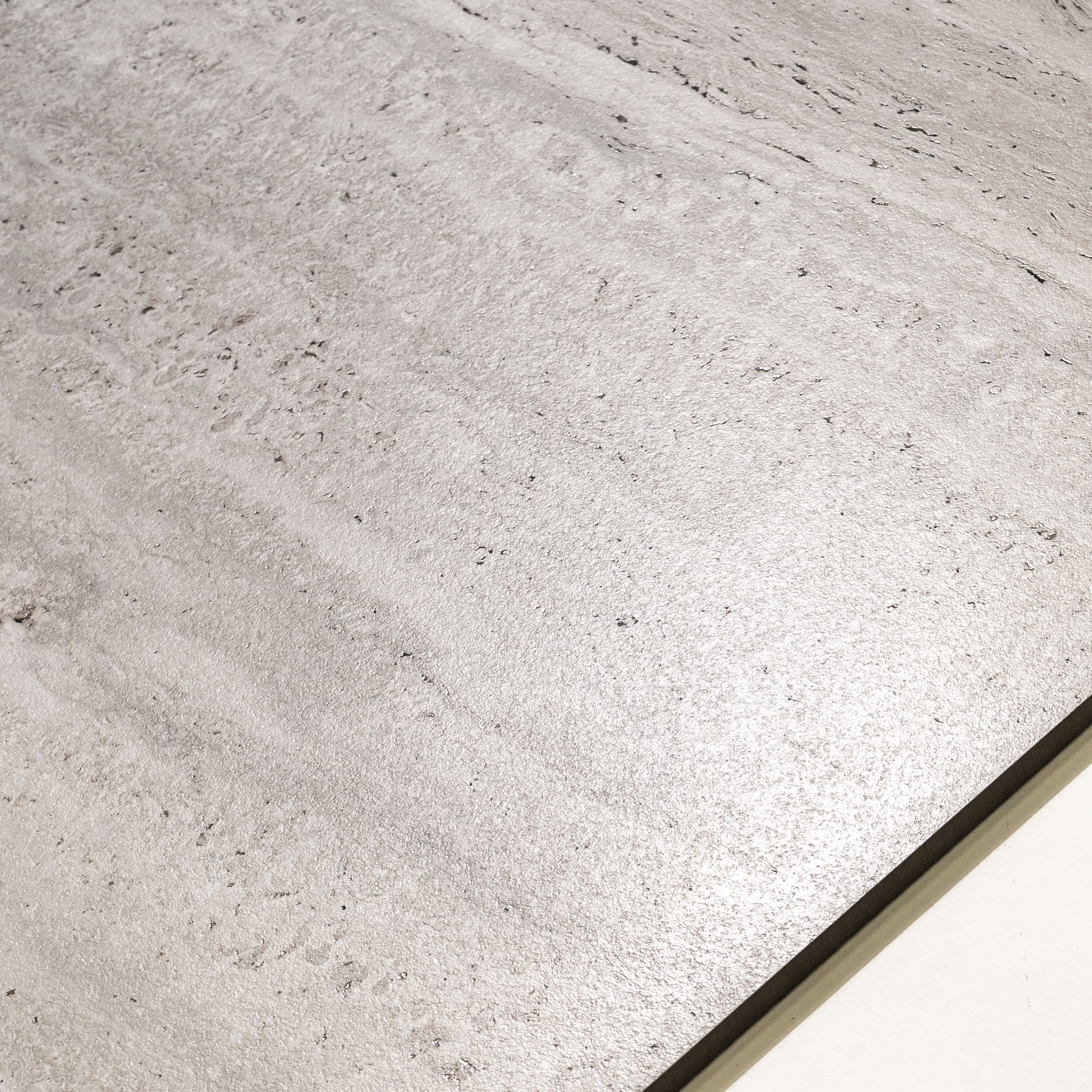Close-up of Roma Travertino Bianco matte porcelain surface revealing authentic travertine pore character and warm cream tonal banding