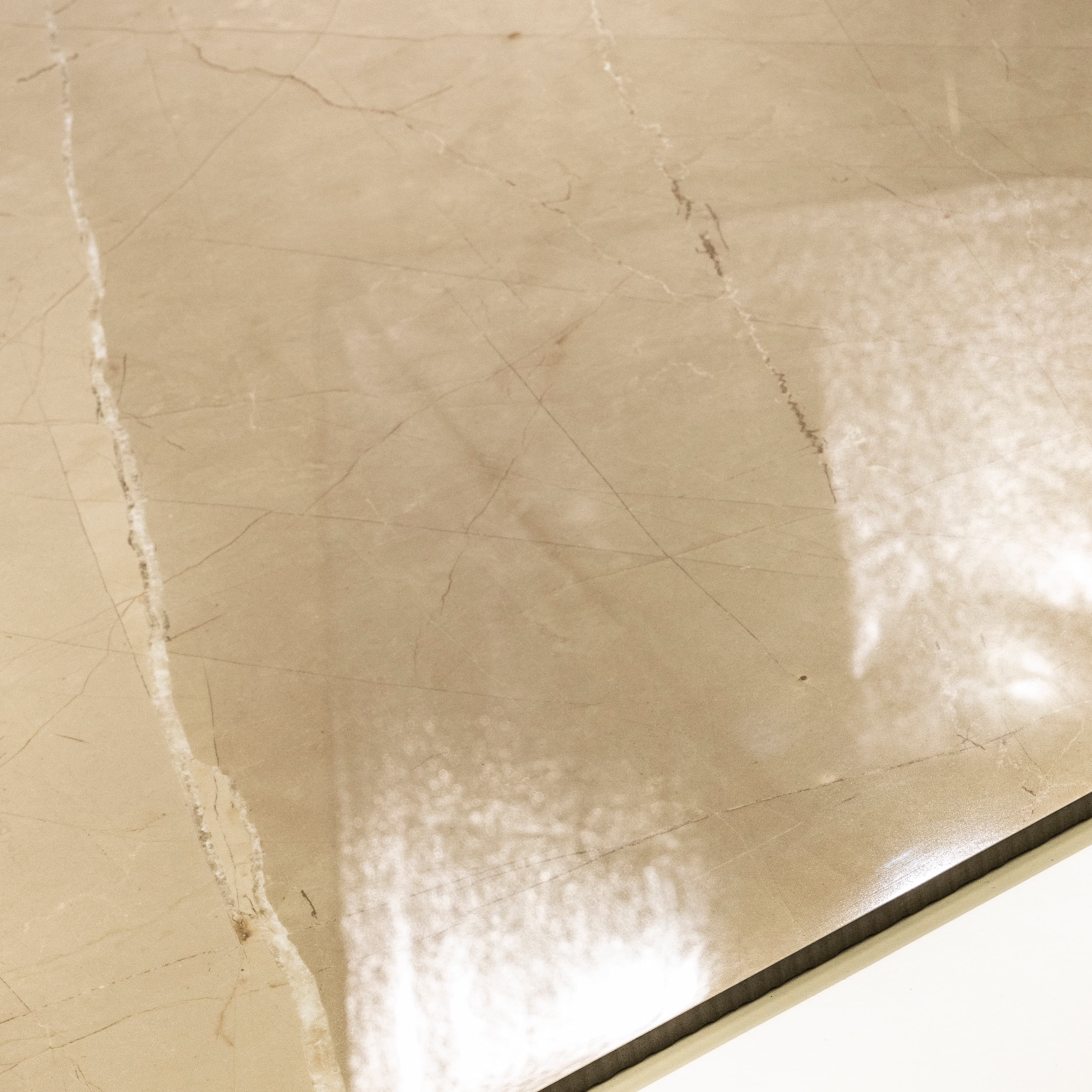 Close-up of Armani Beige high-gloss polished porcelain surface revealing warm sandy tone and delicate marble veining detail