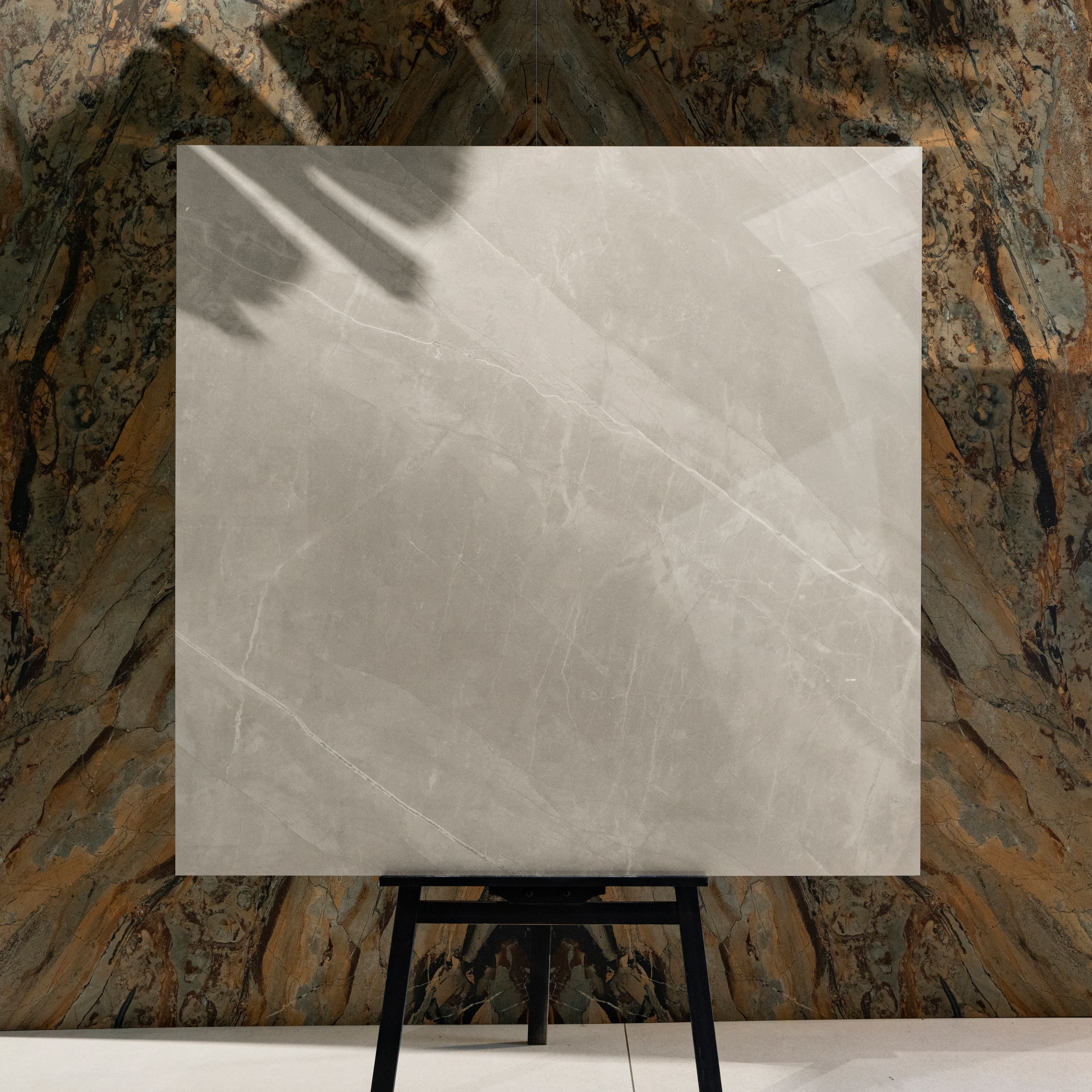 Armani Romano 120x120cm Italian Pietra Grey marble look glossy polished porcelain tile on easel against onyx marble backdrop in UAE luxury tile showroom