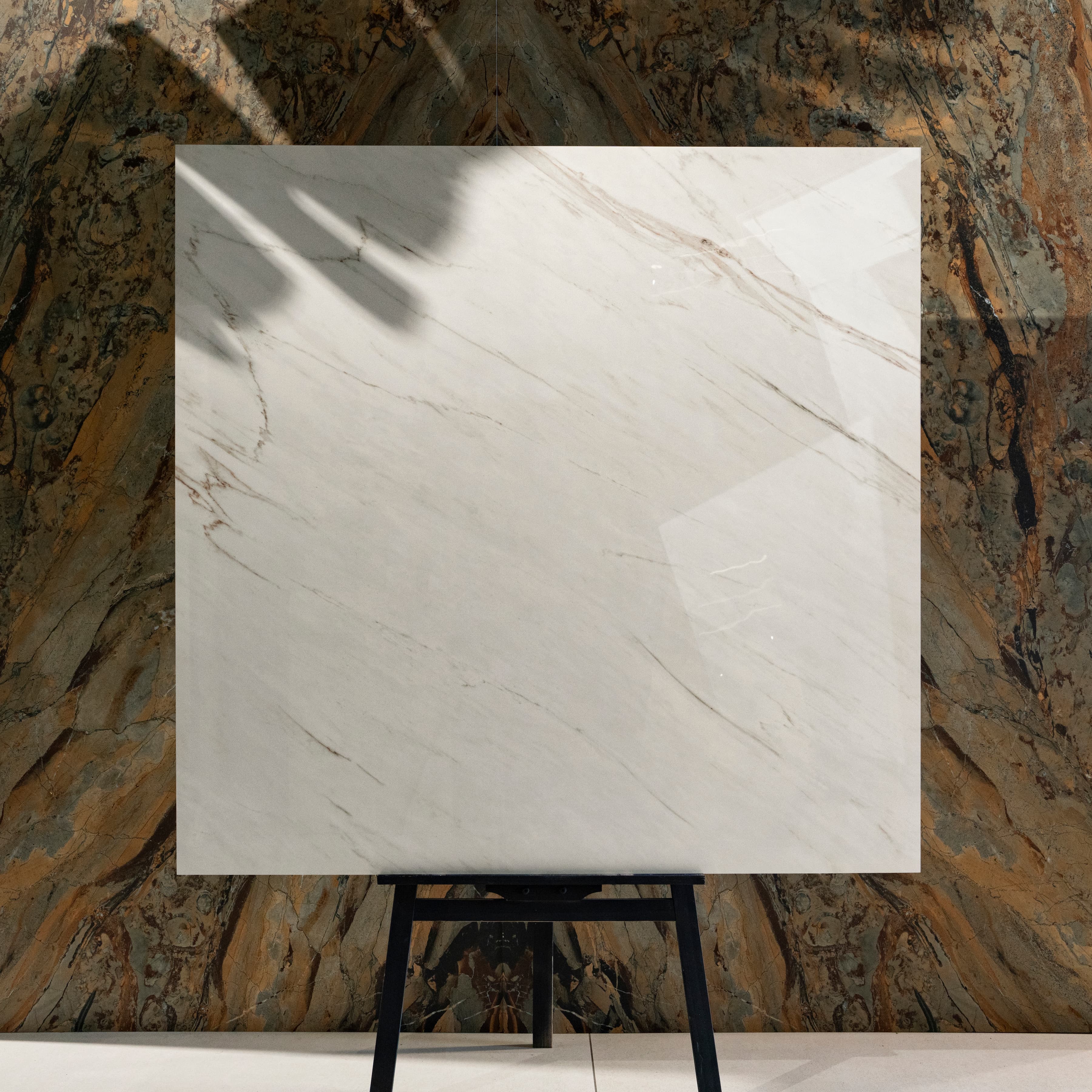 Cavallo 120x120cm Italian warm-veined marble look glossy polished porcelain tile on easel against onyx backdrop in UAE luxury tile showroom