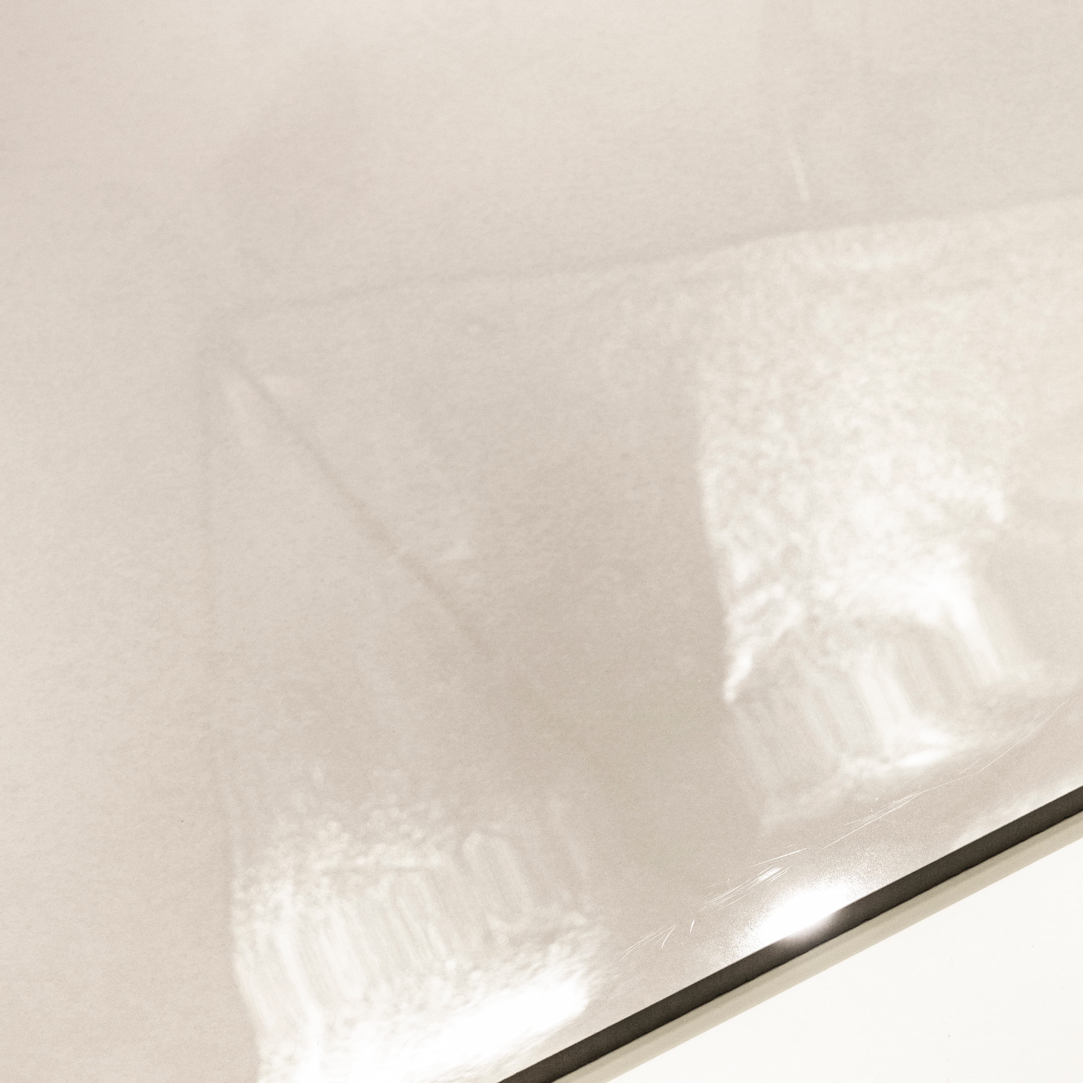 Close-up of Portland Bianco glossy porcelain tile showing mirror-polished cream surface and 9mm thickness