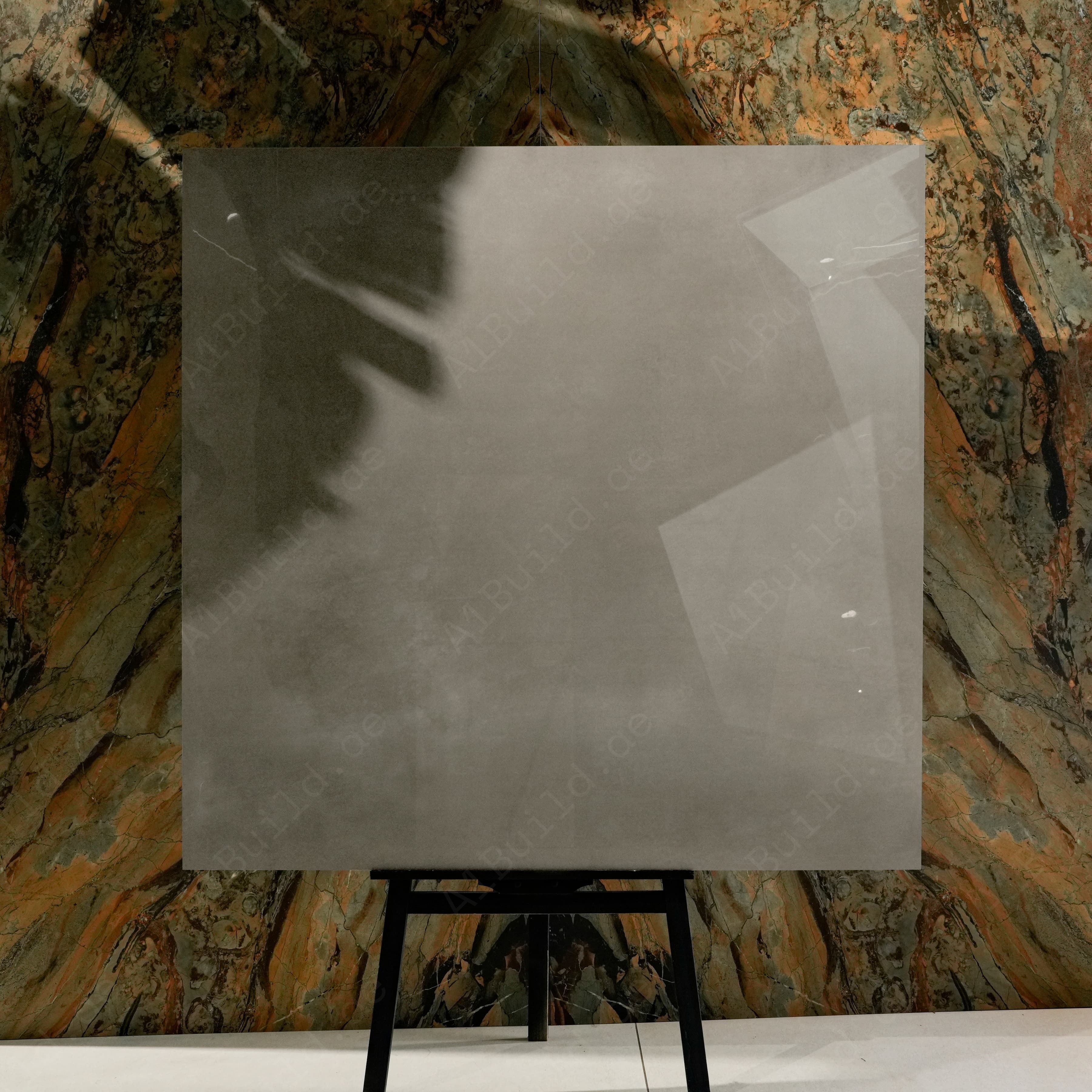 Portland Grey Glossy 120x120 porcelain tile displayed on easel against natural marble backdrop in UAE showroom
